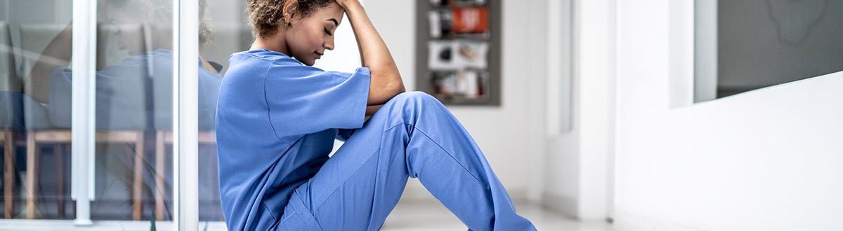 nurse sitting on floor with head in her hands