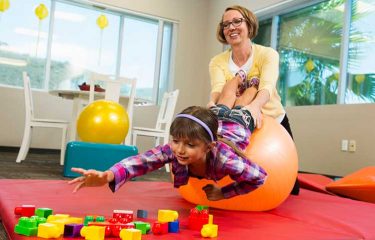 woman with Doctor of Occupational Therapy (OTD) credential playing with child