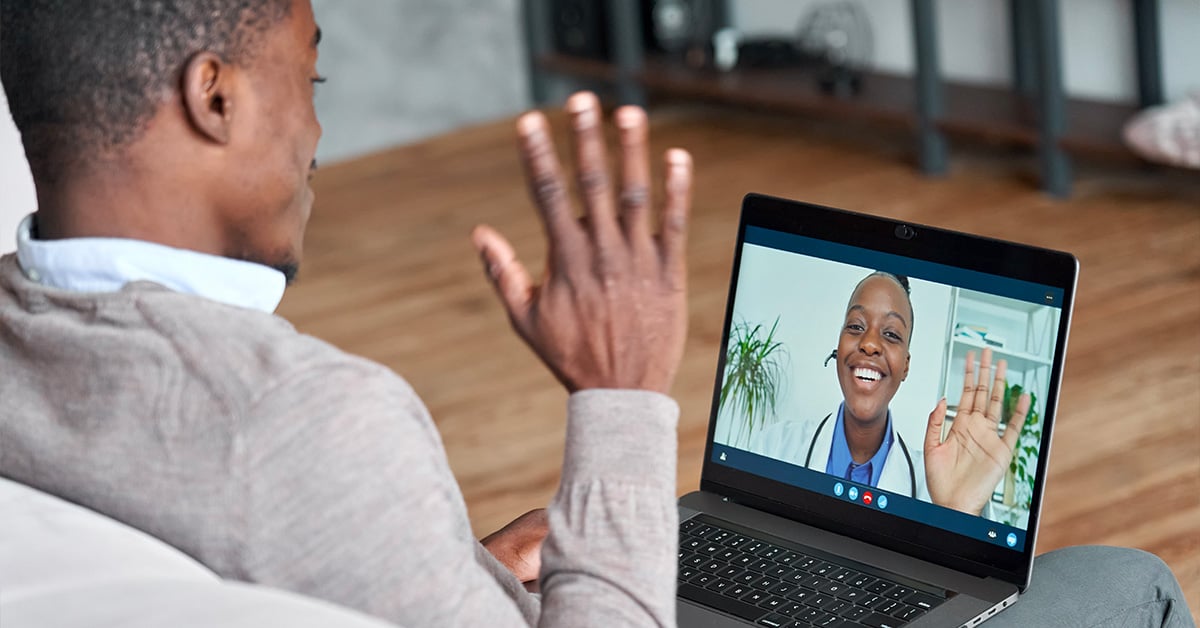A patient is waving to his doctor over a webcam on his laptop. 