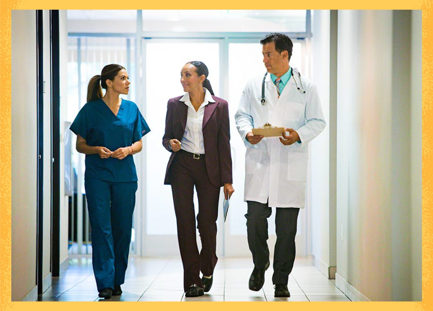 Three medical professionals walking down hallway talking