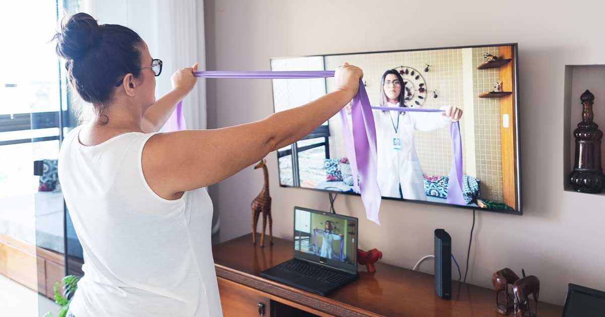 A woman performs an exercise during a virtual occupational therapy appointment. 
