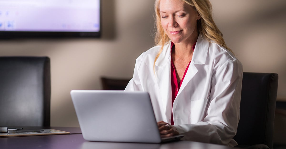 A healthcare professional provides virtual healthcare on a laptop.