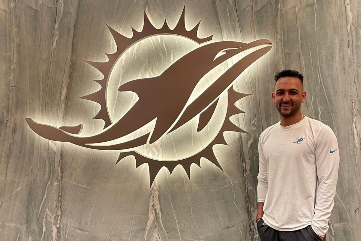 Physical therapy student in front of dolphins football logo.